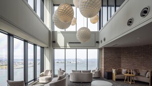 A spacious lounge area with large windows, comfortable seating, and modern pendant lighting. - Tokyu Stay Hakodate Asaichi Akarinoyu (Hakodate)