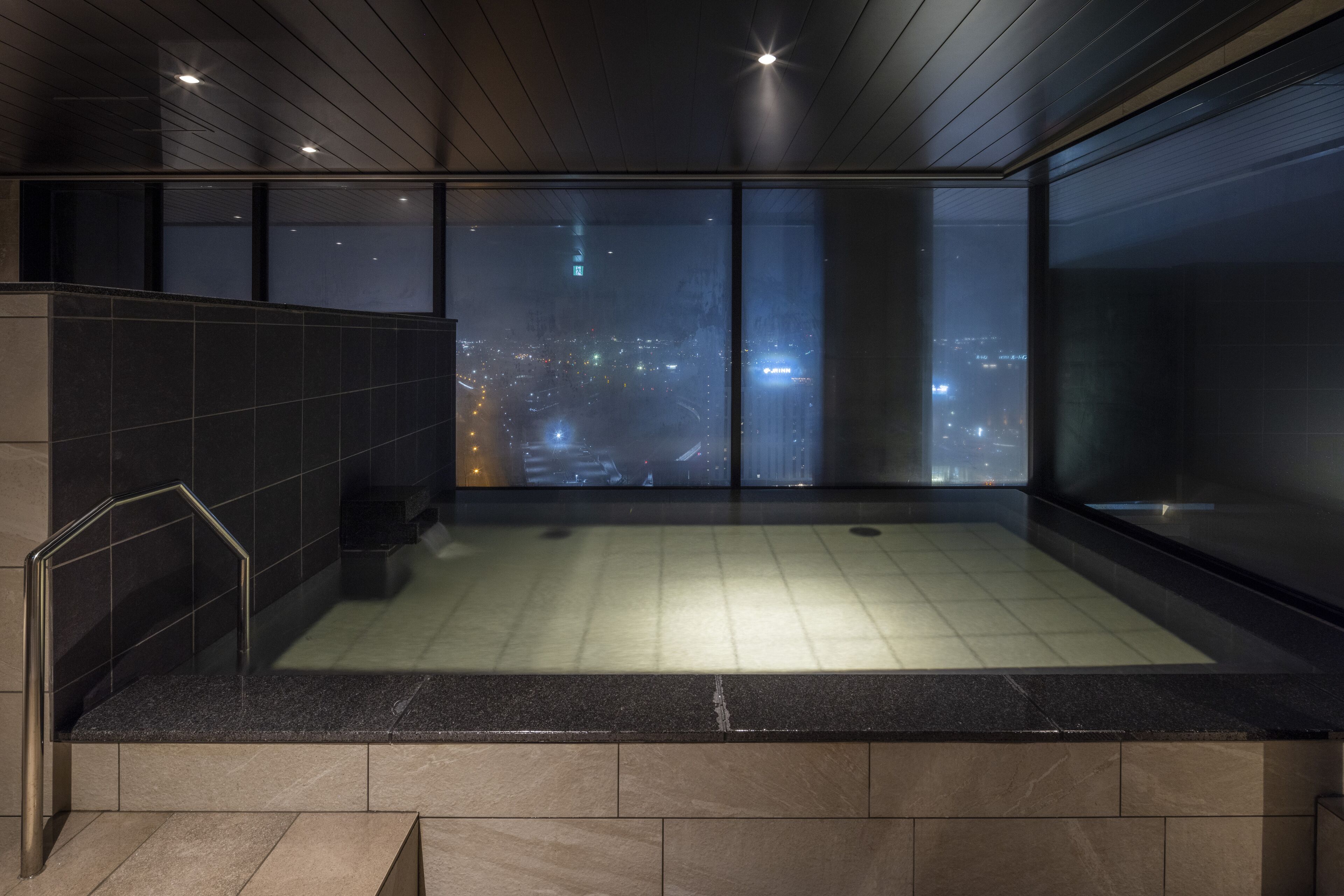 Ein modernes Badezimmer mit einer großen Badewanne, einer Duschkabine aus Glas und Blick auf die Stadt.