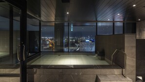 A modern indoor space with a glass wall offering a city view at night. - Tokyu Stay Hakodate Asaichi Akarinoyu (Hakodate)