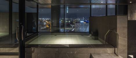 Un espacio interior moderno con una pared de vidrio que ofrece vista a la ciudad de noche.