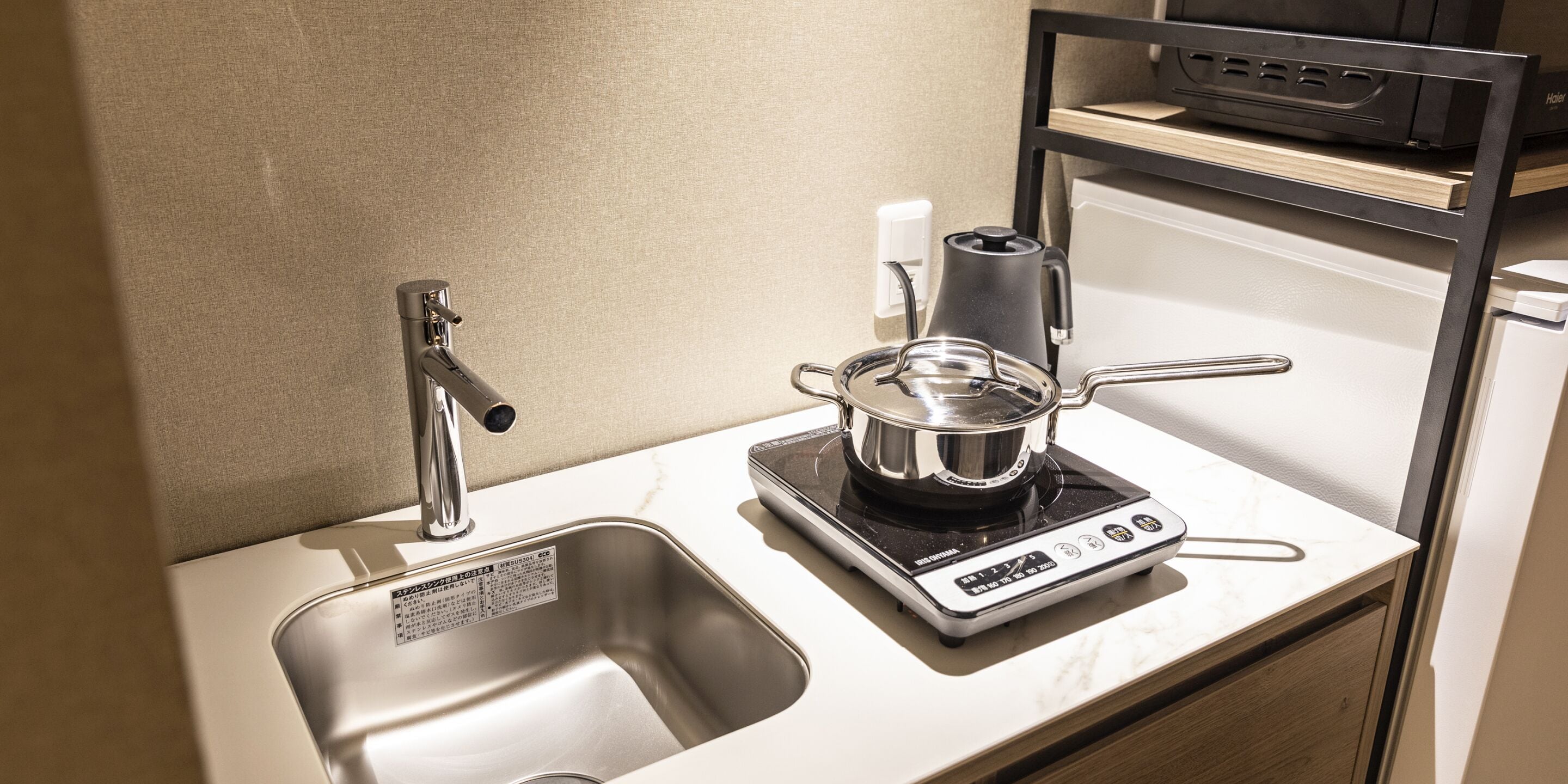 A kitchen with a sink, a kettle, and a coffee maker on a countertop.