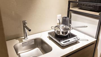 A kitchen with a sink, a kettle, and a coffee maker on a countertop.