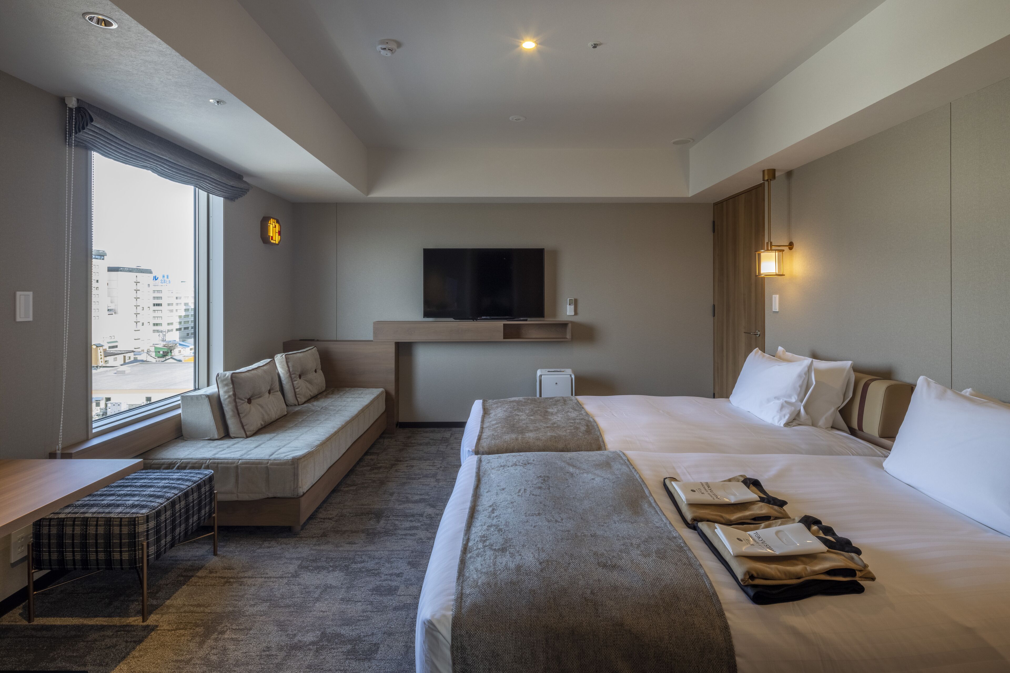 Ett hotellrum med en stor säng, en bäddsoffa, en platt-TV och utsikt över staden.