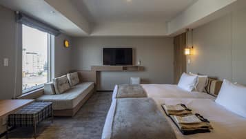 Ett hotellrum med en stor säng, en bäddsoffa, en platt-TV och utsikt över staden.