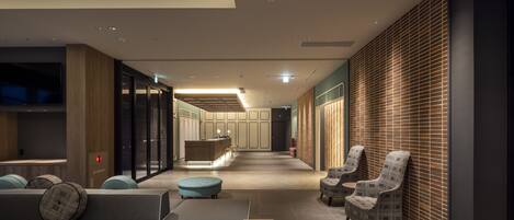 A modern hotel lobby with seating areas, a reception desk, and a large skylight.