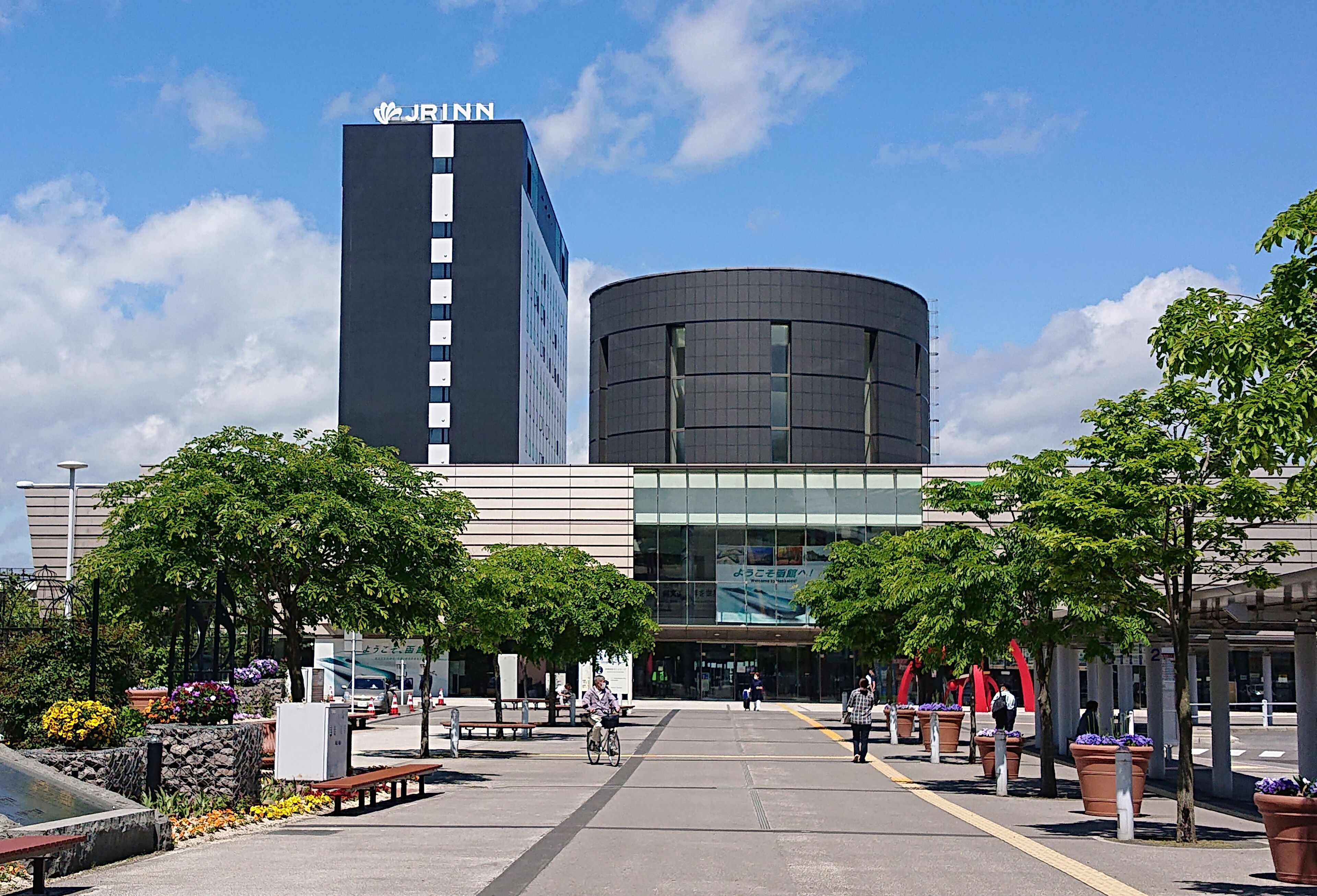 A modern building with a prominent JRNN sign, surrounded by trees and benches.
