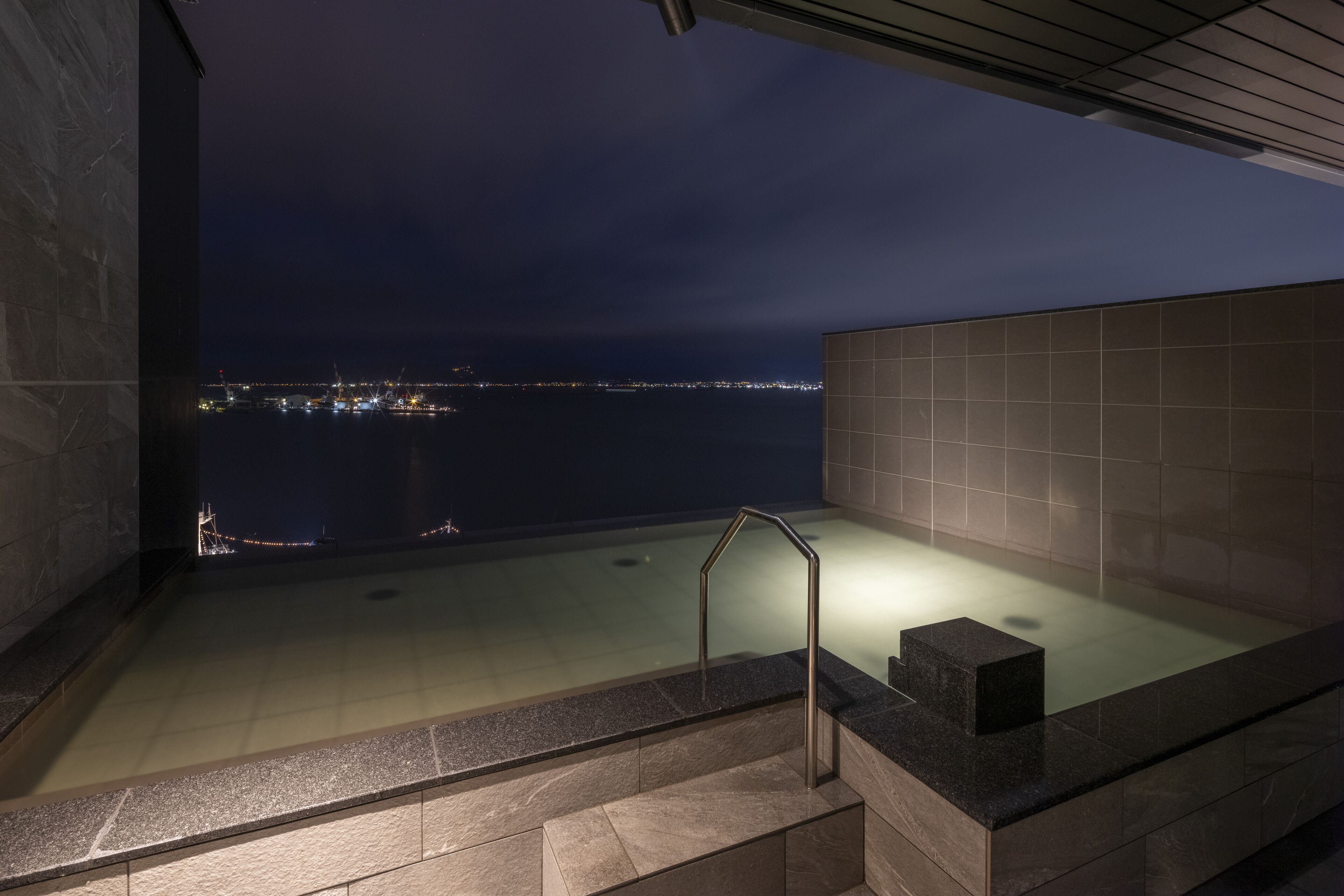 A rooftop pool with a view of the city skyline at night.