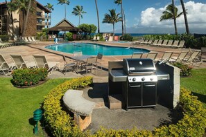 Relax by the pool with ocean views, surrounded by lounge chairs and a barbecue grill.
