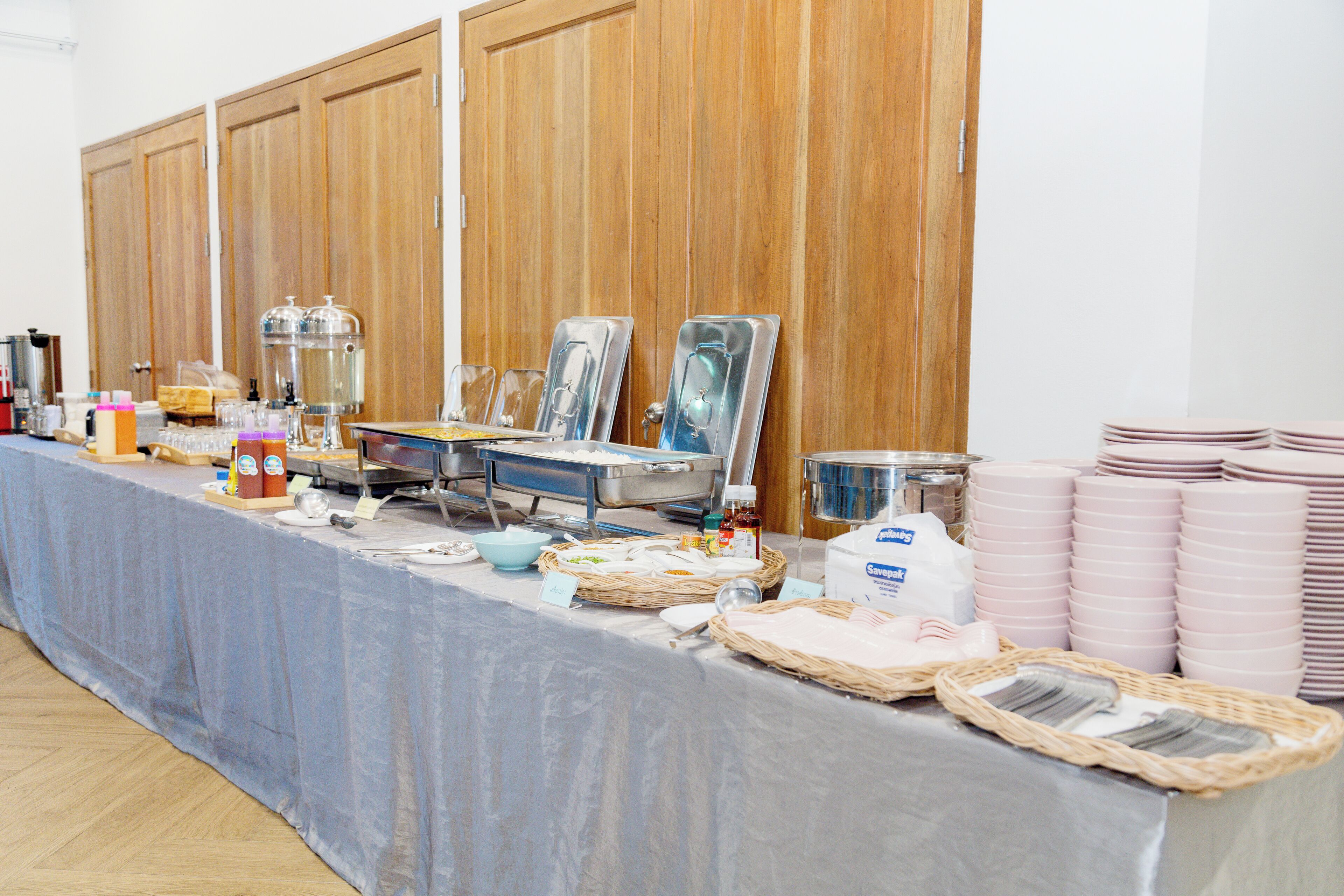 A buffet setup with food containers, serving utensils, and stacked plates.