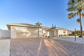 Ein modernes Einfamilienhaus mit Garage, befestigter Auffahrt und einer Palme.
