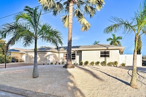 Ein modernes Haus mit Auffahrt, Palmen und Garage.