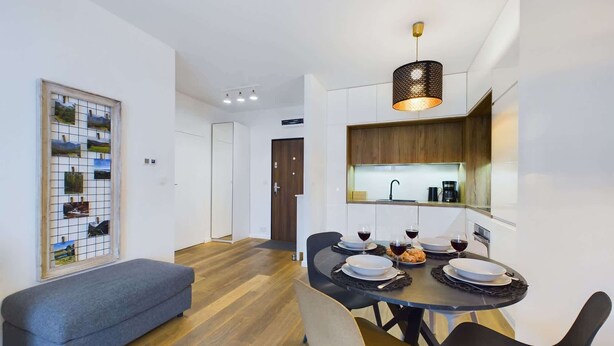 A modern dining area with a round table, chairs, and a pendant light. - Modern apartment in Krakow | Parking | Close to the train station (Kraków)