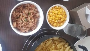 Una mesa con diversos platos, incluyendo pasta, pan y recipientes con diferentes salsas.
