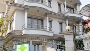 Un edificio de varios pisos con entrada porticada, balcones y un cartel.