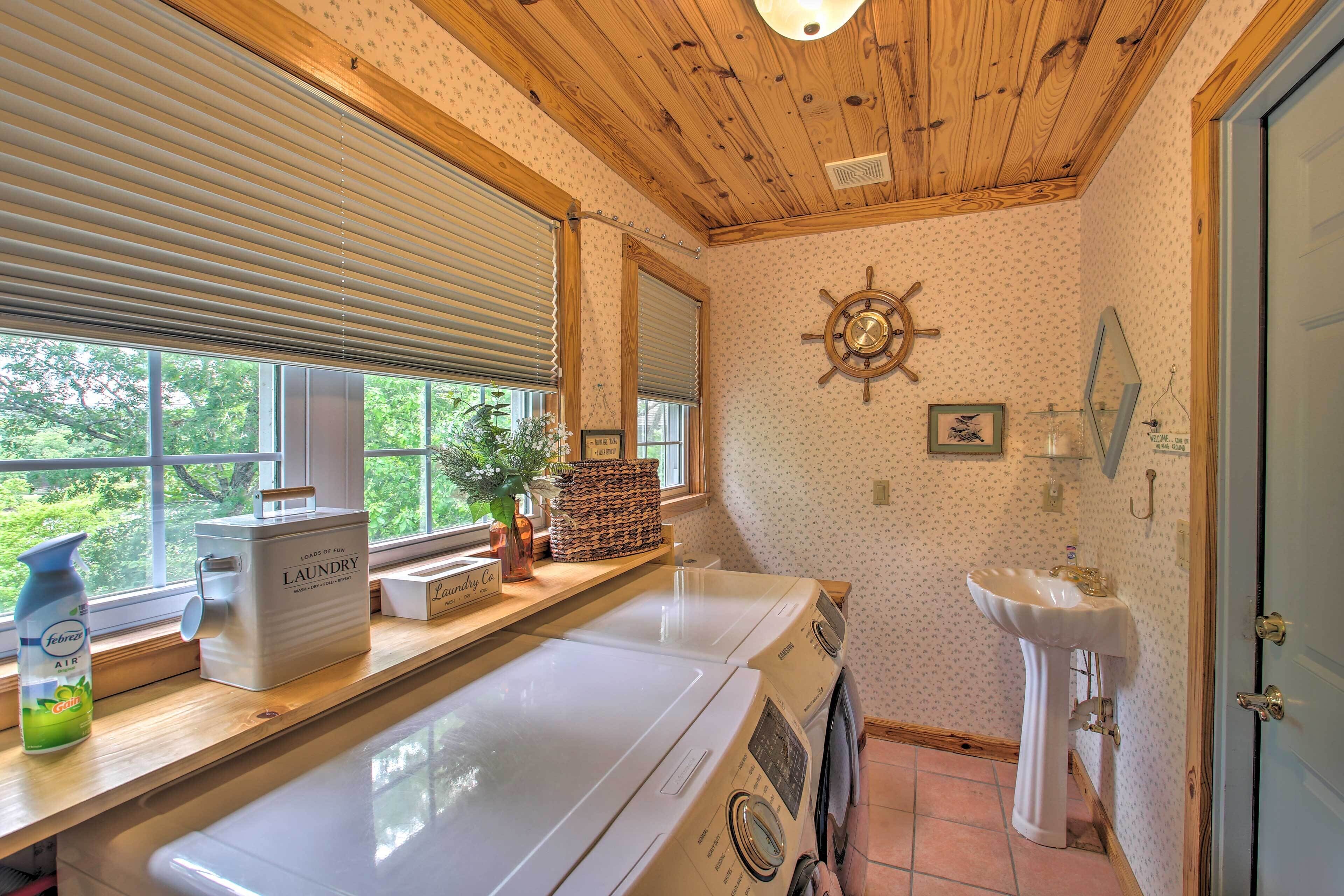 A laundry area with a washing machine, a sink, and a window with blinds.