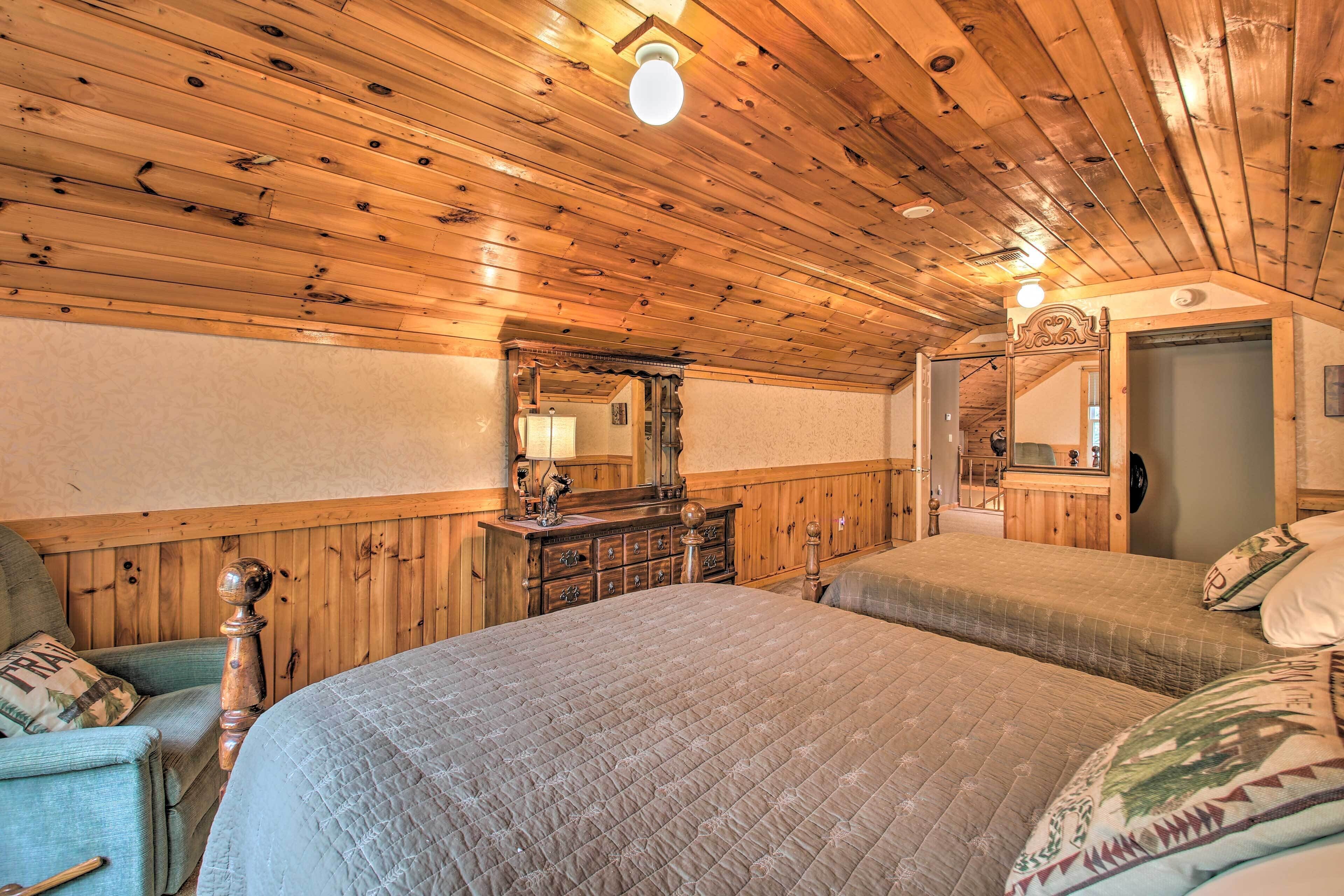 A wooden-paneled room with a bed, dresser, and mirror.