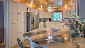 Una cocina amplia con armarios blancos, una isla grande y techo de madera.