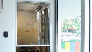A room with a clock, a window, and a door with a sign above it.