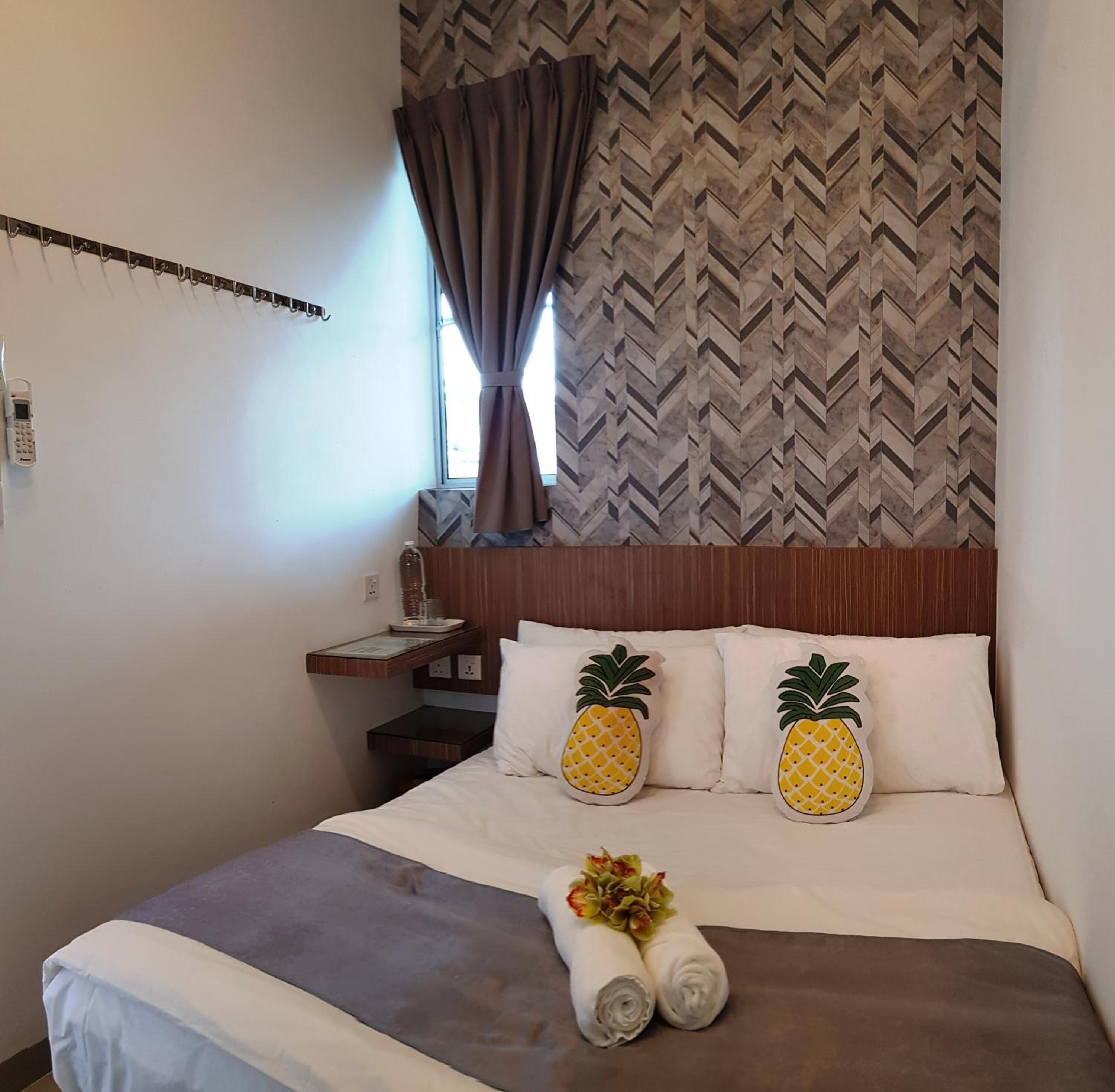 A hotel room with a bed, a nightstand, a phone, and a window with curtains.
