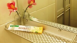 A bathroom with a mirror, a shelf with a toothbrush, and a toothpaste tube.