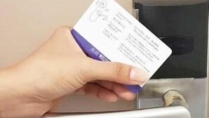 Eine Hand hält eine Karte in der Nähe eines Türgriffs.