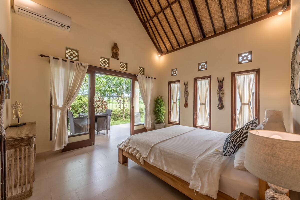 Un dormitorio con una cama grande, un escritorio y vistas al jardín.