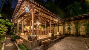 A wooden pavilion with a tiled floor, surrounded by potted plants and a concrete pathway. - Villa Kubu Agung (Ubud)