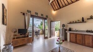 A spacious living area with a television, wooden furniture, and a view to an outdoor patio. - Villa Kubu Agung (Ubud)