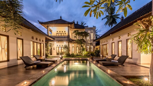A traditional-style building with a swimming pool, lounge chairs, and a well-lit outdoor area. - Villa Kubu Agung (Ubud)