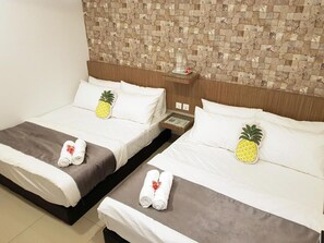 Dos camas individuales con sábanas blancas, cada una con una almohada de piña y toallas enrolladas.