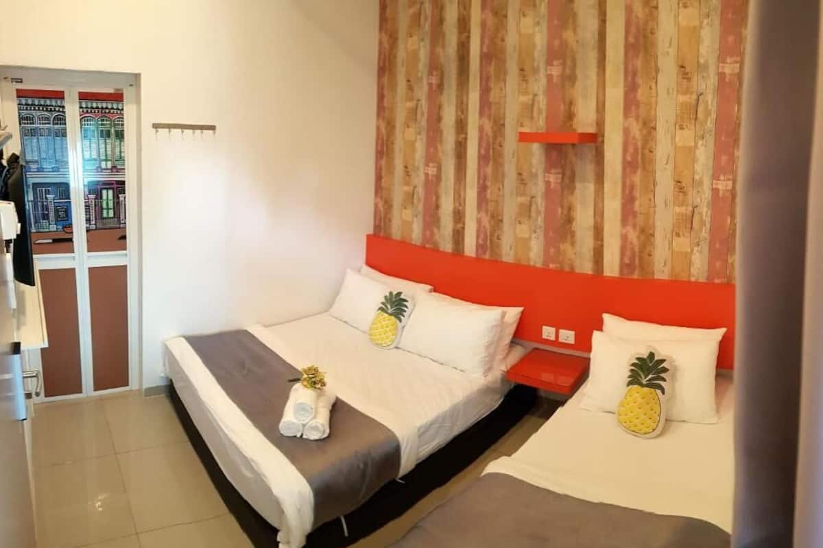 Ett hotellrum med två sängar, var och en med en ananaskudde, en röd sänggavel och ett randigt tapetmönster.