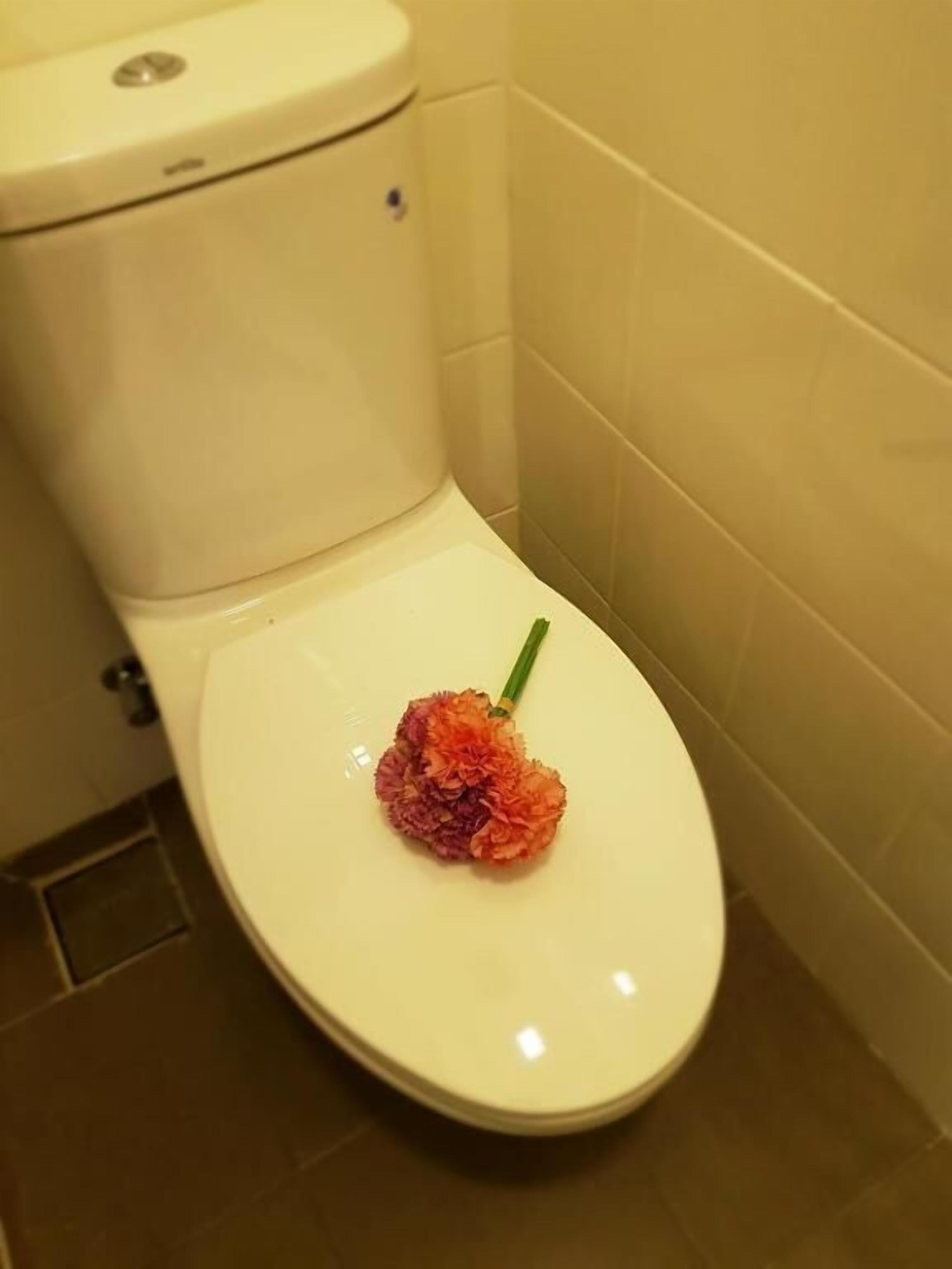 A toilet with a decorative flower arrangement on the seat.