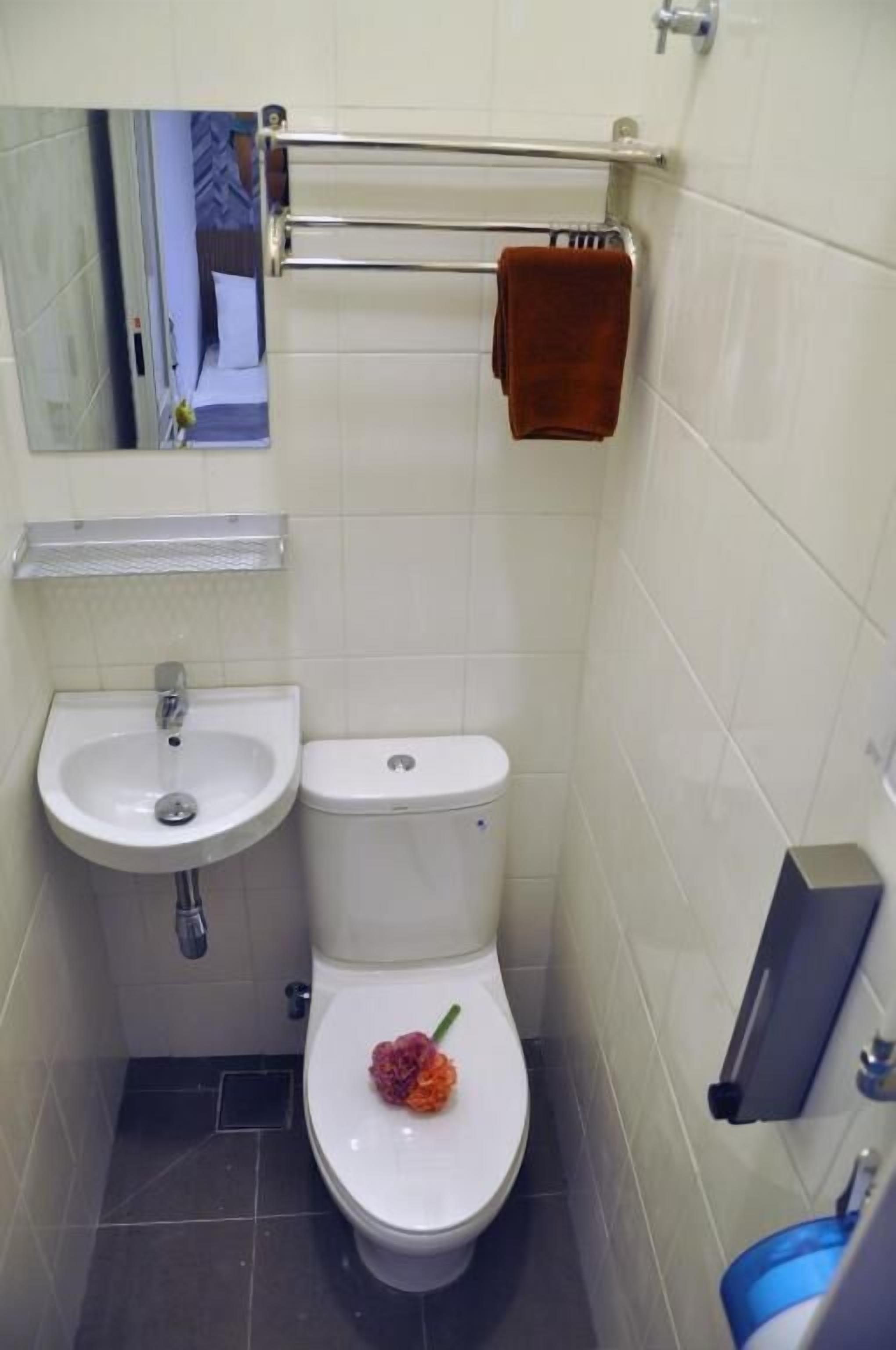 A small bathroom with a white sink, toilet, and a towel rack.