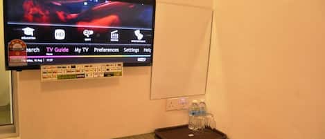 Un televisor en la pared mostrando una película con una barra de menú en la parte inferior.