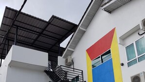 A modern building with a multi-level structure, a prominent geometric facade, and a covered outdoor area with potted plants. - Casa 96 Villa (Kuantan)