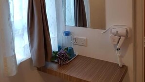 A hotel room with a wooden shelf holding a water bottle, a glass, and a plant. A hairdryer is mounted on the wall. - Casa 96 Villa (Kuantan)