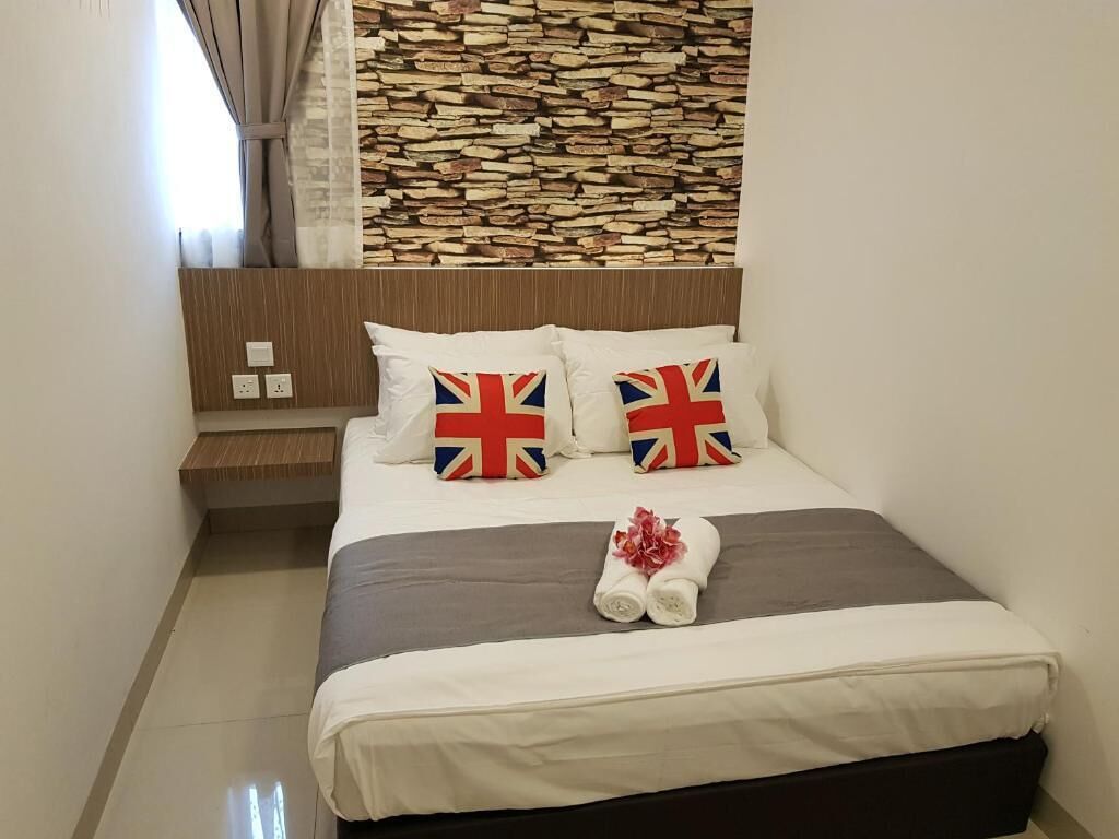 Una cama bien hecha con ropa de cama blanca y dos almohadas con la bandera del Reino Unido.