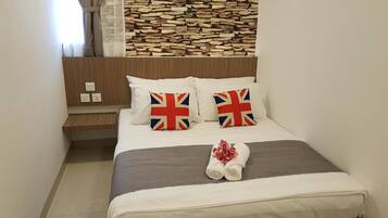 Una cama bien hecha con ropa de cama blanca y dos almohadas con la bandera del Reino Unido.