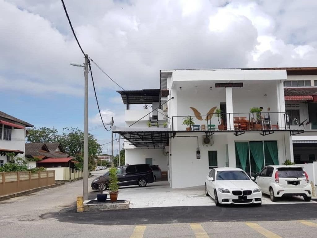 Un edificio moderno de dos pisos con balcón, garaje y estacionamiento para dos autos.