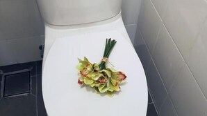 A white toilet with a small sticker on the tank and a bunch of flowers on the seat. - Casa 96 Villa (Kuantan)