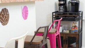 A kitchen with a coffee machine, a shelf with decorative items, and two chairs. - Fun Downtown Home Near Riverwalk (San Antonio)
