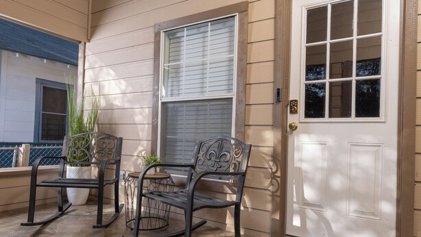 A porch with two rocking chairs, a potted plant, and a white door with a window. - Fun Downtown Home Near Riverwalk (San Antonio)
