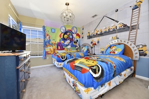 A bedroom with two beds, a TV on a dresser, and a mural on the wall.