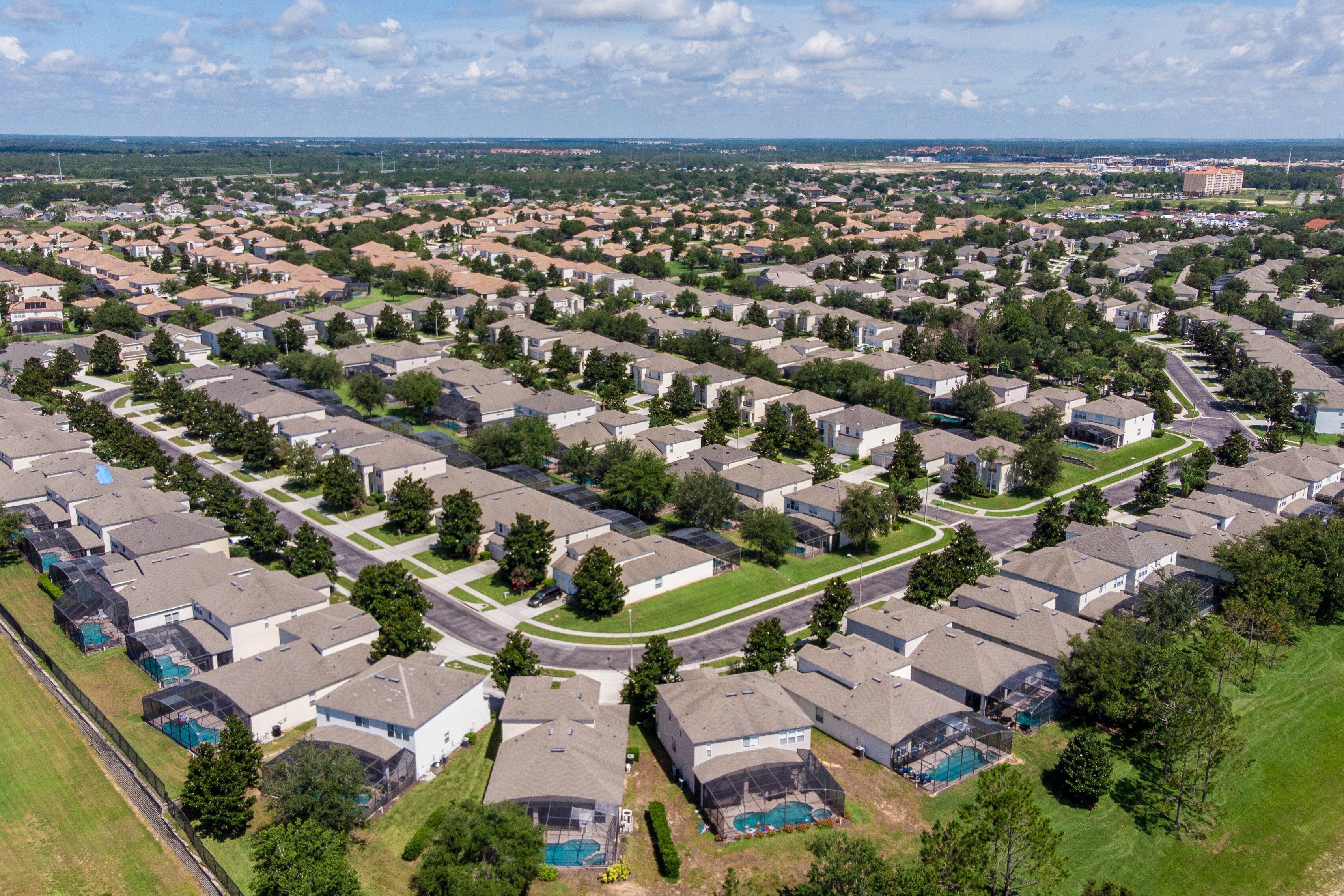 Een woonwijk met meerdere huizen, groene gazons en een heldere lucht.