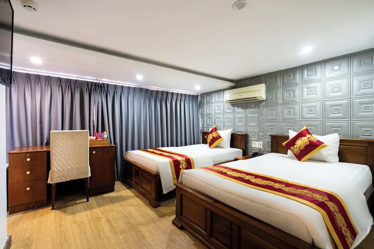 Une chambre d’hôtel avec deux lits, un bureau, une chaise et une armoire.