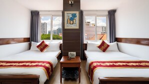 Une chambre d’hôtel avec deux lits, une petite table avec un téléphone et un tableau au mur.