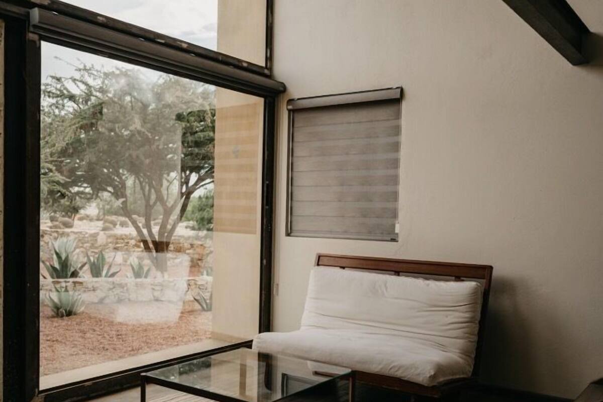 A modern room with a glass door leading to a garden, a wooden floor, and a simple glass coffee table.