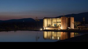 A modern building with a glass facade, a brick structure, and a reflection in a body of water. - Mineral del Cielo (Pozos)