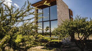 A modern building with large windows and stone walls, surrounded by trees. - Mineral del Cielo (Pozos)