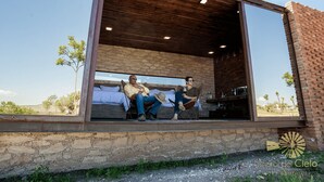 A modern building with a large glass window, a stone exterior, and a wooden ceiling. - Mineral del Cielo (Pozos)